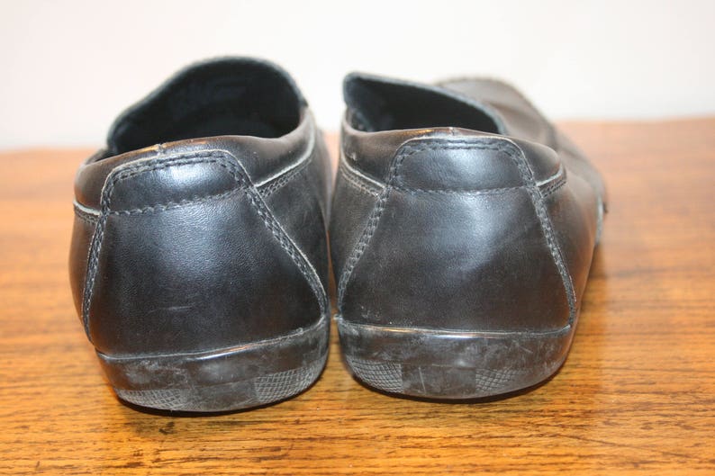 Puede incluir: Un par de zapatos negros de cuero sin cordones con punta redonda.