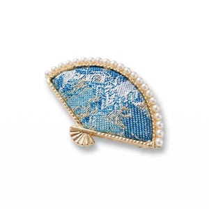 May include: A fan-shaped brooch with a gold-tone frame and a blue and white patterned fabric design. The edge is lined with small, round, faux pearls. The brooch has a decorative, fan-shaped base.