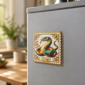 May include: A square refrigerator magnet shaped like a postage stamp featuring a colourful, coiled snake with a protruding tongue. The design includes gold-toned floral accents in the corners and the Chinese characters 已蛇 printed at the bottom.