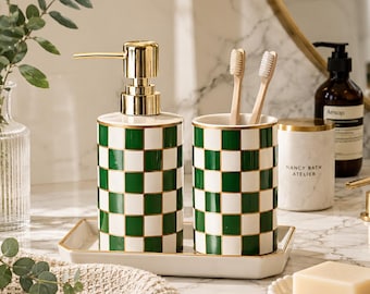 Juego de baño de cerámica con diseño de tablero de ajedrez y dispensador de jabón dorado.
