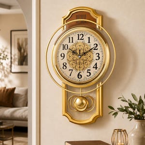 May include: A wall clock with a gold frame and a circular face featuring black Arabic numerals. The centre has a gold floral pattern. A gold pendulum with concentric rings hangs below the clock face, which is mounted on a rectangular wood panel.
