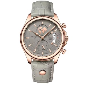 May include: A rose gold-tone wristwatch with a gray face and a gray leather band. The watch face features multiple subdials, a world map graphic, and the text "Loedagar 1853". The band has a textured, crocodile-like pattern.