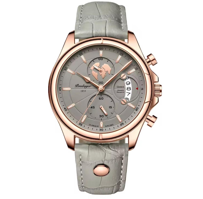 May include: A rose gold-tone wristwatch with a gray face and a gray leather band. The watch face features multiple subdials, a world map graphic, and the text "Loedagar 1853". The band has a textured, crocodile-like pattern.