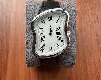 Zegarek w stylu vintage z przetopionymi cyframi rzymskimi, koperta w kolorze srebrnym, pasek z czarnej skóry, surrealistyczny styl artystyczny