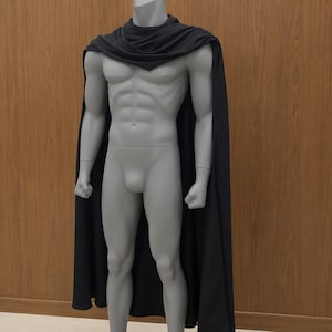 May include: A solid black cape draped over the shoulders of a grey, muscular, full-body mannequin. The cape features a simple, unadorned design that hangs straight down from the neck, covering the back and sides of the mannequin's torso and legs.