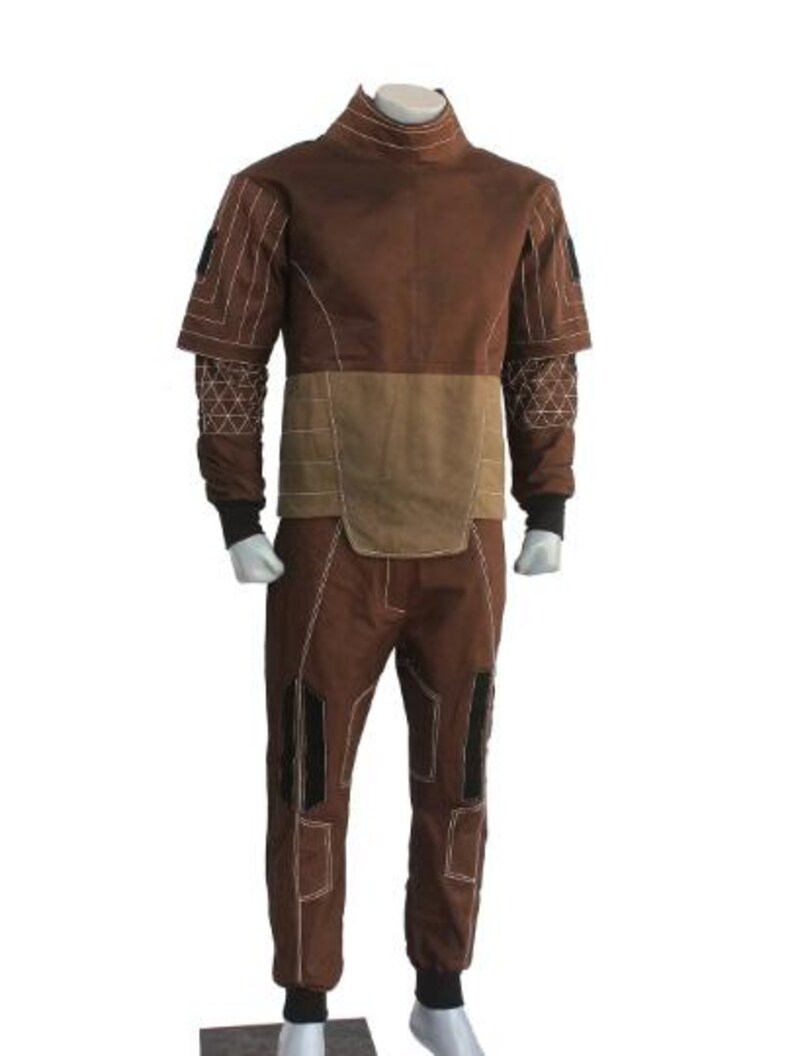 May include: Brown jumpsuit with a high collar and tan accents. The suit features white stitching details, black cuffs, and knee patches. The sleeves have a unique design with geometric patterns.