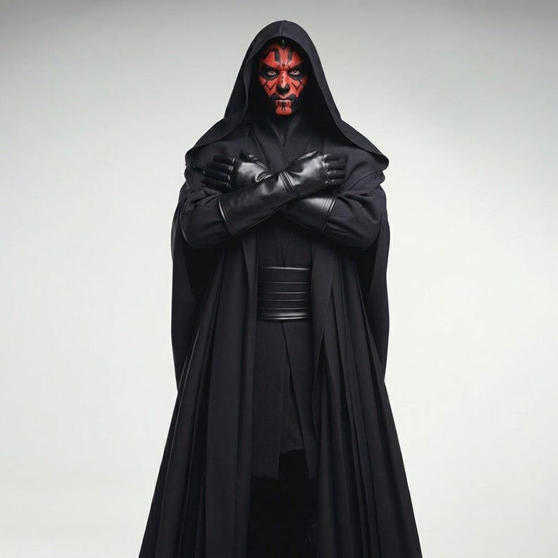 May include: A figure in a black hooded cloak and gloves, with red and black facial markings. The person has their arms crossed. The outfit includes a wide belt and a long, flowing cloak. The background is plain white.