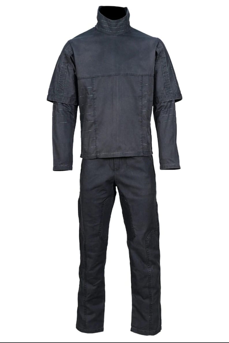 K&ouml;nnte beinhalten: Ein dunkelgraues zweiteiliges Outfit. Das Oberteil hat einen hohen Kragen, kurze &Auml;rmel &uuml;ber langen &Auml;rmeln und sichtbare N&auml;hte. Die passende Hose hat verst&auml;rkte Kniepatches. Das Outfit ist auf Zweckm&auml;&szlig;igkeit und Haltbarkeit ausgelegt.