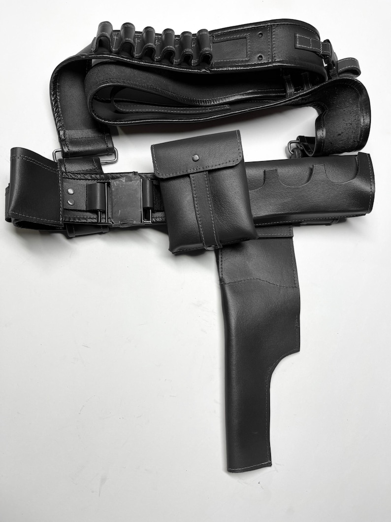 Pu&ograve; includere: Una cintura tattica in pelle nera con pi&ugrave; tasche, una fondina e porta cartucce. La cintura presenta una chiusura con fibbia ed &egrave; progettata per trasportare vari oggetti. La pelle sembra liscia e resistente.