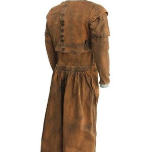 May include: A brown, vintage-style costume with a long skirt and jacket. The jacket has structured shoulders and a button detail. The fabric has a distressed appearance, with darker shading in areas. The costume is displayed on a mannequin.