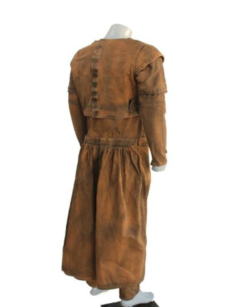 May include: A brown, vintage-style costume with a long skirt and jacket. The jacket has structured shoulders and a button detail. The fabric has a distressed appearance, with darker shading in areas. The costume is displayed on a mannequin.