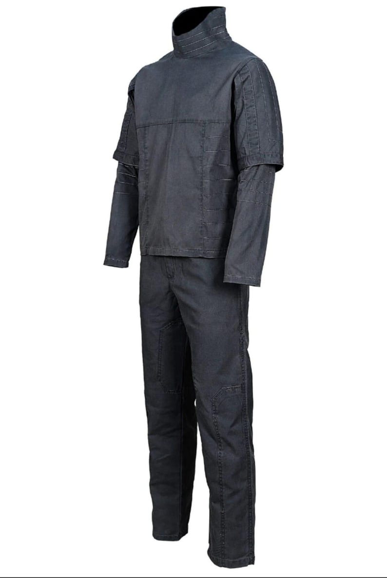K&ouml;nnte beinhalten: Ein dunkelgraues zweiteiliges Outfit. Das Oberteil hat einen hohen Kragen und geschichtete &Auml;rmel. Die Hose hat verst&auml;rkte Kniepatches. Das Outfit ist aus strapazierf&auml;higem Stoff gefertigt, geeignet f&uuml;r Arbeit oder Kost&uuml;me.