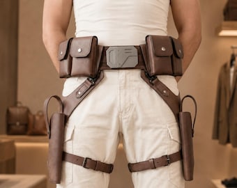 May include: A brown leather utility belt featuring four rectangular pouches with snap closures, a central metallic buckle with geometric detailing, and two integrated holsters with adjustable leg straps secured by metal buckles.
