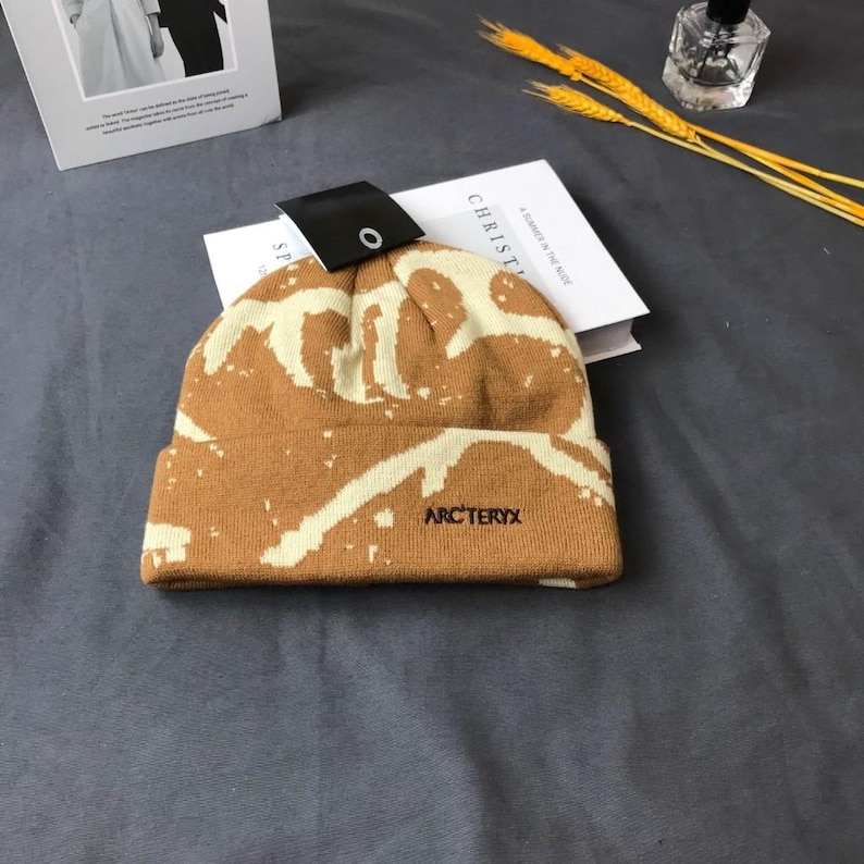 Peut inclure: Un bonnet marron et cr&egrave;me avec le nom de la marque "Arc'teryx" brod&eacute; sur le devant. Le chapeau pr&eacute;sente un motif unique et est fait d'un mat&eacute;riau tricot&eacute;. Une &eacute;tiquette noire est attach&eacute;e au chapeau.