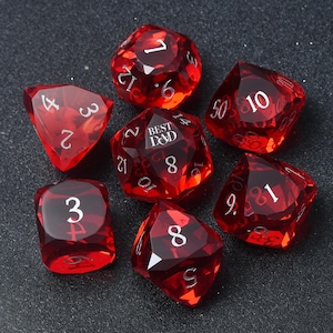 Può includere: Set di sette dadi poliedrici rossi traslucidi, per giochi di ruolo. Ogni dado presenta numeri bianchi e un design sfaccettato. Un dado reca la scritta "BEST D&D". I dadi sono esposti su uno sfondo scuro.