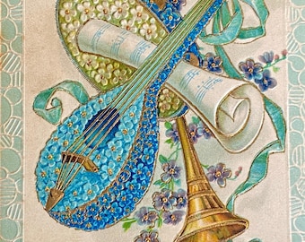 Wytłoczona francuska pocztówka antyczna, trio instrumentów muzycznych: mandolina, tamburyn i róg, niezapominajki // Wydrukowano w Prusach, ostemplowano w 1907 r.