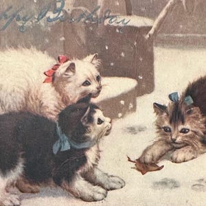 Puede incluir: Ilustración vintage de tres gatitos jugando en la nieve. Un gatito blanco con un lazo rojo, un gatito blanco y negro con un lazo azul y un gatito atigrado marrón con un lazo azul. La imagen tiene un ambiente suave y nostálgico.