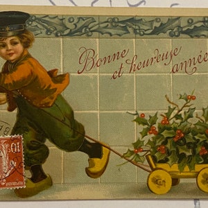 Cartão postal francês de jovem rapaz, brincando de maquinista puxando carrinho cheio de azevinho, cartão postal antigo de feliz ano novo de 1910