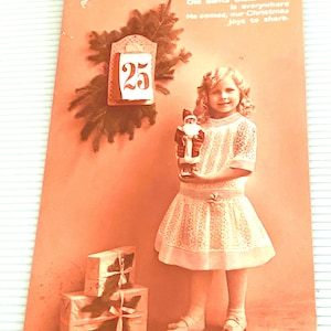 Postal de saludos navideños, niña con figura de Papá Noel, postal antigua