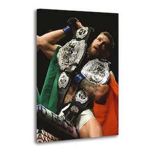 Peut inclure: Impression sur toile d'un artiste martial mixte tenant des ceintures de champion. L'image montre l'athlète avec un drapeau irlandais sur les épaules. Les ceintures sont noires avec des détails argentés.
