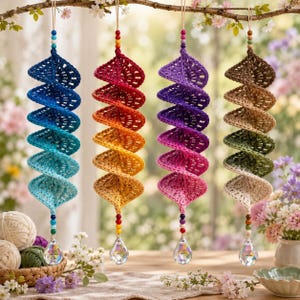 May include: Four hanging spiral ornaments made of crocheted yarn in gradient color schemes. Each ornament features a vertical row of colorful beads at the top and bottom, ending with a clear, faceted crystal prism drop hanging from the base.