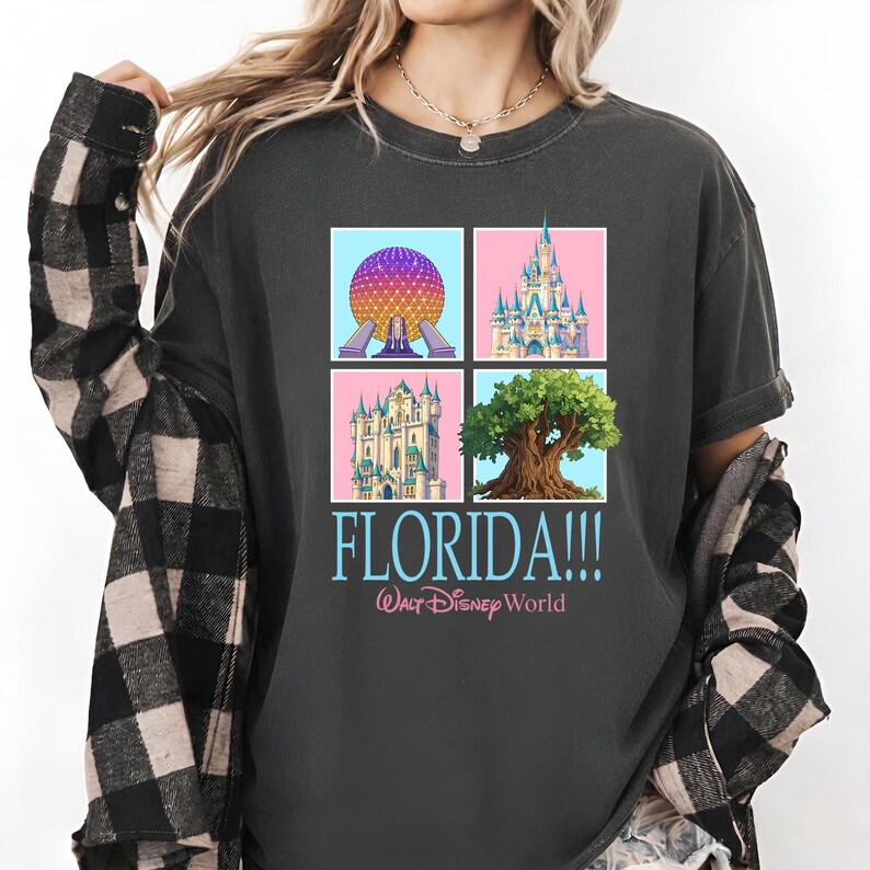 May include: Dark gray t-shirt featuring four square images of Florida landmarks. The shirt includes the text "FLORIDA!!!" in blue and "Walt Disney World" in pink. The images include a sphere, a castle, and a tree.
