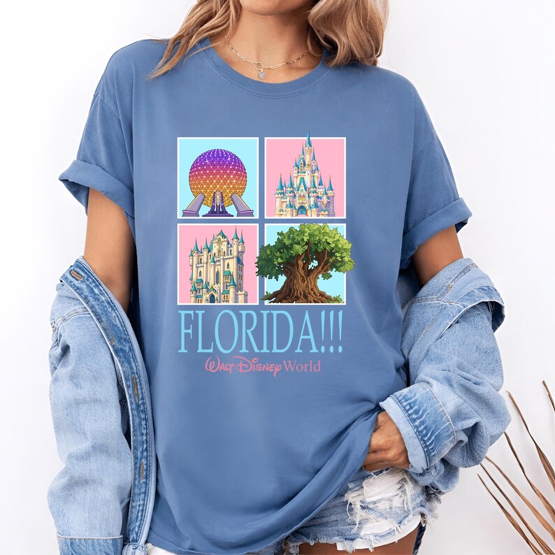 May include: A light blue t-shirt featuring four colorful squares with iconic Florida landmarks. The shirt has the word "FLORIDA!!!" and "Walt Disney World" printed in a stylized font.