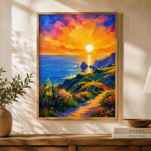 Op de afbeelding: Een rechthoekige wandkunstprint met een impressionistisch landschapsschilderij van een levendige zonsondergang boven de oceaan. De scène toont een heldere gele zon, oranje en roze wolken, diepblauw water en een pad door kleurrijke bloemen.
