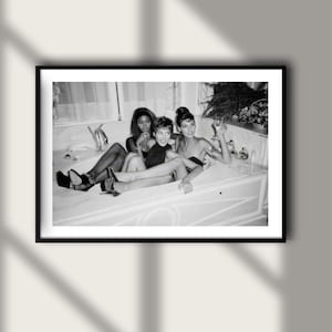 Può includere: Stampa incorniciata in bianco e nero con tre persone in una vasca da bagno. Le persone indossano abiti neri e tengono in mano dei bicchieri. La stampa è esposta su una parete bianca con un'ombra.