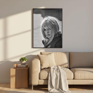 K&ouml;nnte beinhalten: Eine wei&szlig;e Keramiktasse mit schwarzem Henkel und dem Text "But First, Coffee" in fetter, schwarzer Schrift. Die Tasse steht vor einem verschwommenen Hintergrund, der eine gem&uuml;tliche Umgebung suggeriert.