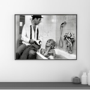 May include: Black and white framed print featuring a vintage photograph of a man and a woman. The woman is in a bathtub, and the man is sitting nearby. The image has a classic, cinematic feel.