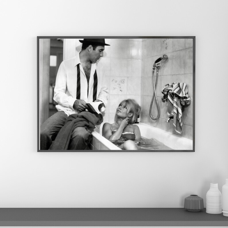 May include: Black and white framed print featuring a vintage photograph of a man and a woman. The woman is in a bathtub, and the man is sitting nearby. The image has a classic, cinematic feel.