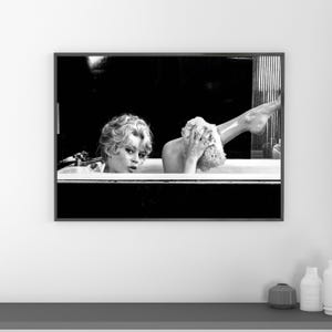 Puede incluir: Impresi&oacute;n enmarcada en blanco y negro de una mujer en una ba&ntilde;era. La mujer se lava la pierna con una esponja. La imagen es una fotograf&iacute;a vintage.