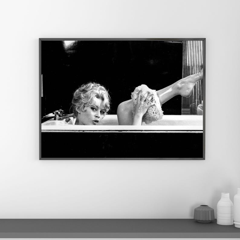 Puede incluir: Impresi&oacute;n enmarcada en blanco y negro de una mujer en una ba&ntilde;era. La mujer se lava la pierna con una esponja. La imagen es una fotograf&iacute;a vintage.