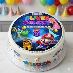 May include: A round white cake decorated with a Super Mario Galaxy theme. The cake features a colorful image of Mario, Luigi, Yoshi, and other characters. The cake is decorated with the name "Oliver" and the number "5".