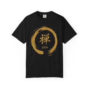 May include: Black t-shirt with a gold-colored Zen circle design. The design features a gold brushstroke circle with the Japanese character for Zen and the English word "ZEN" below it. The shirt is a short-sleeved crew neck.