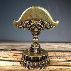 Peut inclure: Un objet décoratif doré détaillé avec un design orné. L'objet présente un dessus large et incurvé, des sculptures complexes et une base ronde. La base est soutenue par un piédestal avec des motifs détaillés. Le design suggère un artefact religieux ou cérémoniel.