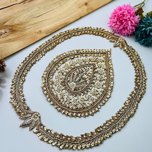 May include: A gold embroidered applique set featuring a circular border and a central teardrop-shaped piece. Both elements are decorated with metallic gold thread, small white beads, and sequins arranged in intricate floral and leaf patterns.