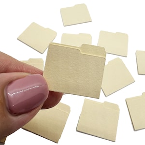 May include: A collection of small, rectangular, cream-colored paper file folders, each featuring a single tab on the top right edge. These miniature stationery items are arranged in a scattered pattern, showcasing their simple, flat, and uniform design.