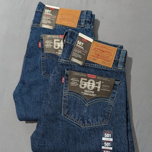 May include: Two pairs of dark blue Levi's 501 Original jeans. Each pair has a classic five-pocket design, a button fly, and the Levi's brand label on the back. The jeans have tags with the size 32x30.