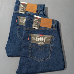 May include: Two pairs of blue denim jeans with tags. The jeans have a classic five-pocket design and a straight leg fit. The tags read "501 Original" and "Levi's Premium Collection". The jeans are folded neatly.