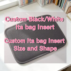 Könnte beinhalten: Ein rechteckiger, dunkelgrauer Ita-Tascheneinsatz mit einer strukturierten Netzoberfläche und abgerundeten Ecken. Der Text Custom Black/White Ita bag Insert und Custom Ita bag Insert Size and Shape ist in rosa Schrift über das Objekt gelegt.