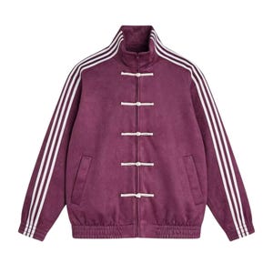 May include: A maroon track jacket with white stripes on the sleeves and a mandarin collar. The jacket features a full-length zip and white frog closures down the front. It has two front pockets and a ribbed hem and cuffs.