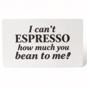 Puede incluir: Una tarjeta rectangular blanca con esquinas redondeadas presenta el texto "I can't ESPRESSO how much you bean to me!" en negro y negrita. La tarjeta est&aacute; sobre un fondo blanco liso.