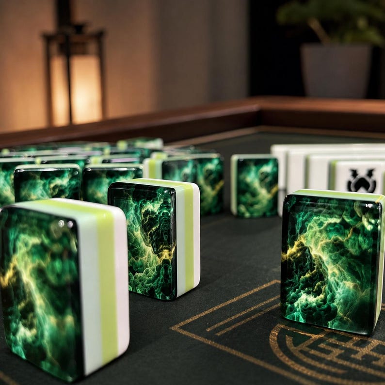 May include: A set of rectangular mahjong tiles featuring a deep green and gold swirling nebula pattern on the front face, with white and light green side panels, arranged on a dark surface with gold line markings and a white tile with a black icon.