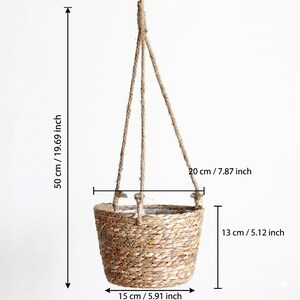 May include: A hanging woven basket with a natural fiber rope. The basket is 5.91 inches wide, 5.12 inches tall, and 7.87 inches across. The total hanging length is 19.69 inches. The basket is made of a light brown woven material.