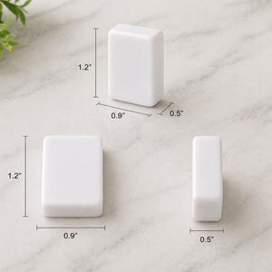 May include: Three white rectangular objects are displayed, each with rounded edges. The dimensions are provided: 1.2 inches in height, 0.9 inches in width, and 0.5 inches in depth. The objects are arranged on a light-colored surface.