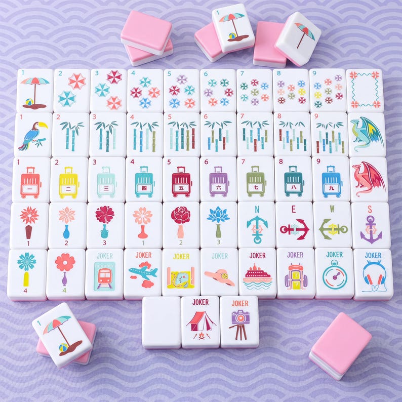 May include: A set of white mahjong tiles with pink backs, featuring colorful illustrations of beach umbrellas, bamboo stalks, suitcases, flowers, anchors, and travel-themed icons like airplanes, cameras, and tents, with some tiles labeled Joker.
