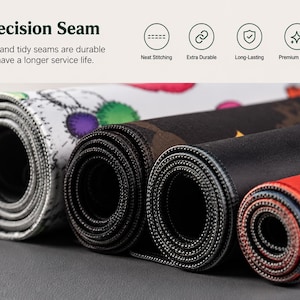 Op de afbeelding: Vier opgerolde bureaumatten met diverse grafische patronen en kleuren, waaronder wit, zwart en rood. De matten hebben een precisienaad langs de randen met nette stiksels. De tekst op de afbeelding luidt Precision Seam, Neat Stitching, Extra Durable, Long-Lasting, Premium Quality.