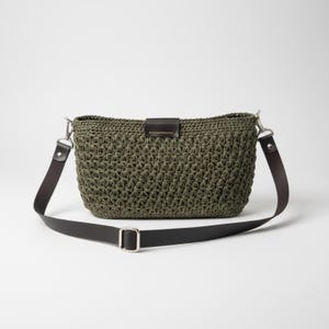 Pode incluir: Bolsa crossbody de crochê verde oliva com aba e detalhes da alça em couro marrom escuro. A bolsa possui fivela e ferragens prateadas. A alça ajustável permite usá-la no ombro ou na transversal. A bolsa tem aprox. 30 cm de largura e 20 cm de altura.